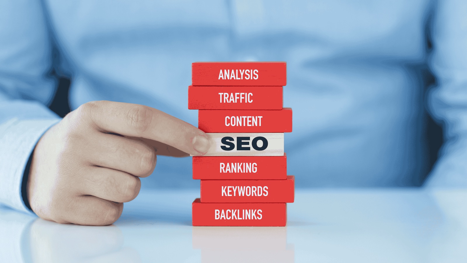 Hand selecting 'SEO' from a stack of blocks labeled with digital marketing elements
