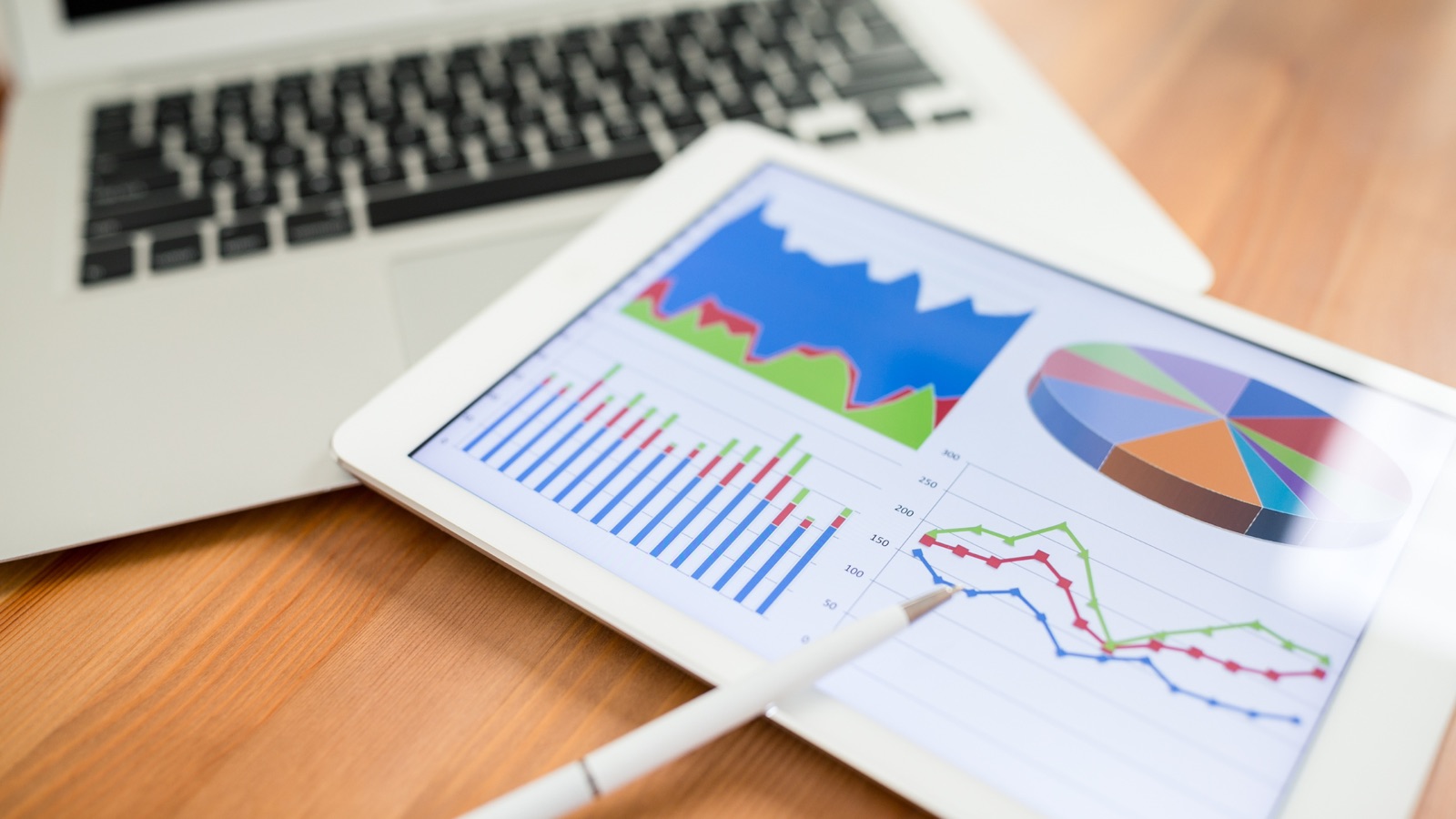 Tablet displaying analytics charts next to a laptop, representing digital marketing data